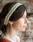 A close up shot of Marina wearing the Bournlet headband. She is side on to the camera, her hair is tied back to showcase the cream, cable knit headband