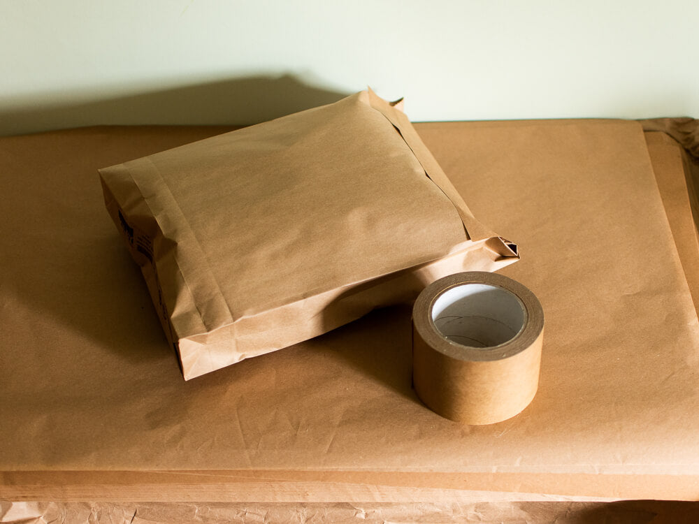 A simple image of a brown paper package next to a roll of paper tape