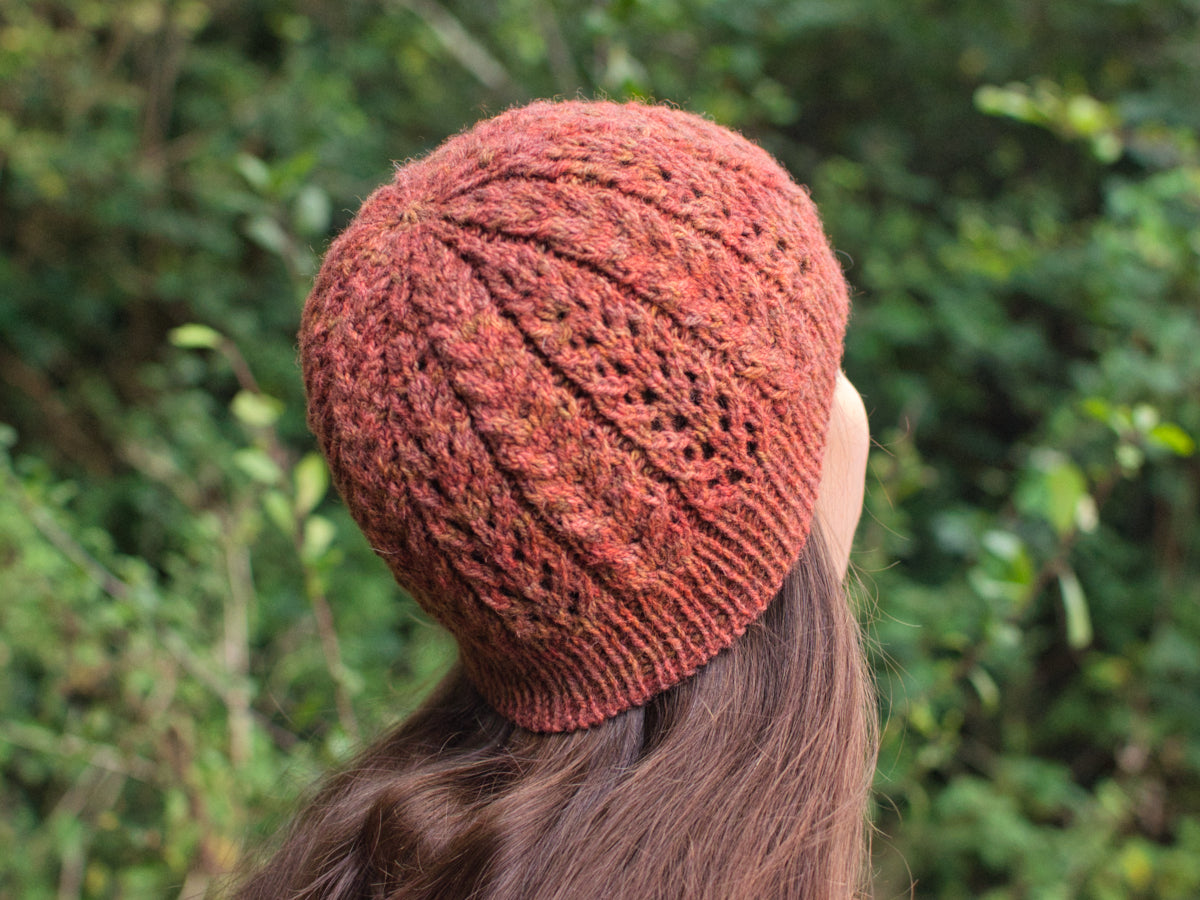 Lace and cabled hat knitted in hand-dyed orange DK yarn