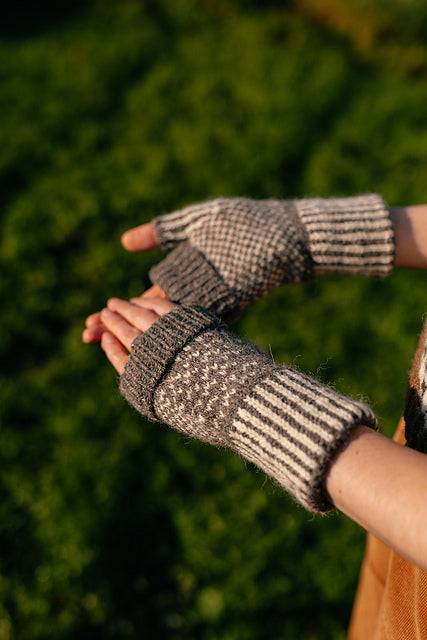 a close up image of a pair of colourwork mitts knit in sheepy shades. 
